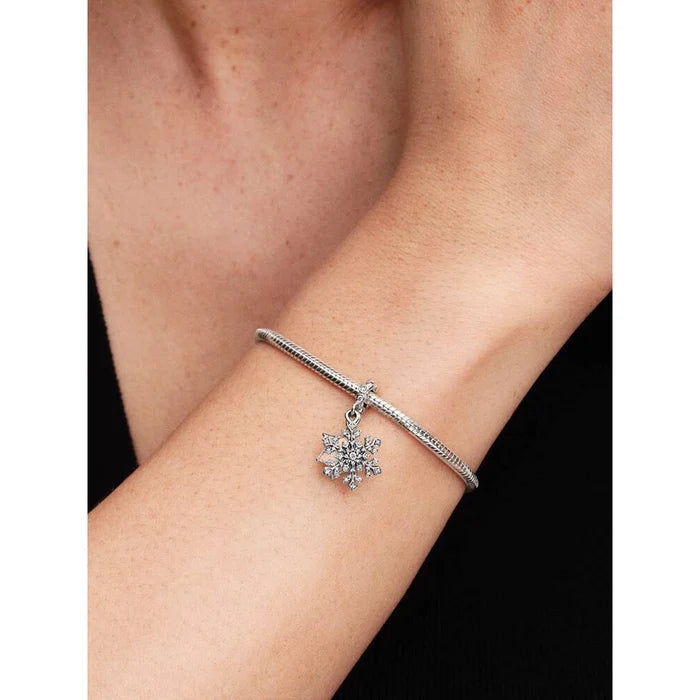 Pandora Opalescent Snowflake Double Dangle Charm worn on a wrist with a sterling silver bracelet.