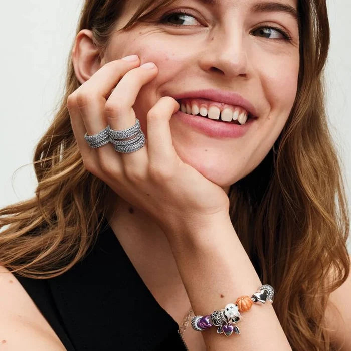 A woman with a bright smile wears a bracelet, highlighting her joyful expression and fashionable choice of jewelry.