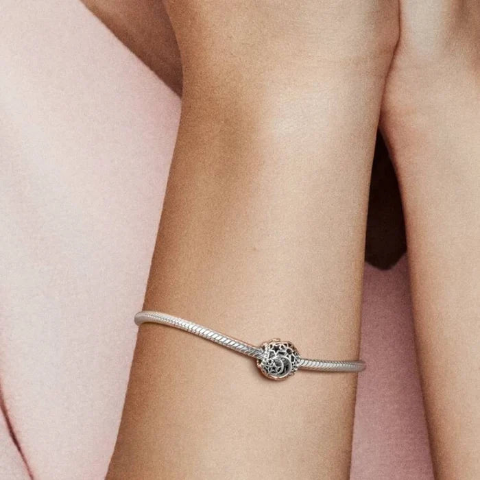 A woman smiles while wearing a stylish bracelet on her wrist, showcasing her joyful expression and elegant accessory.