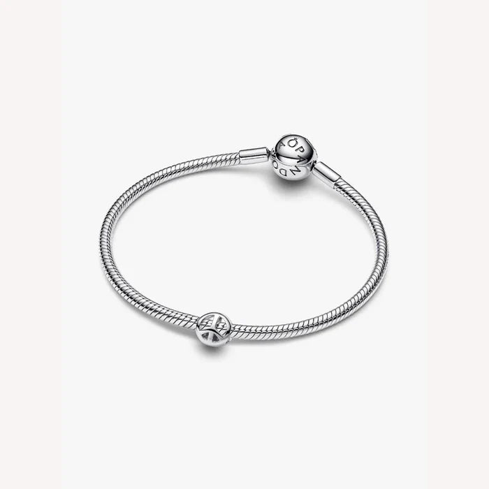 Silver bracelet with a peace symbol charm on a light background