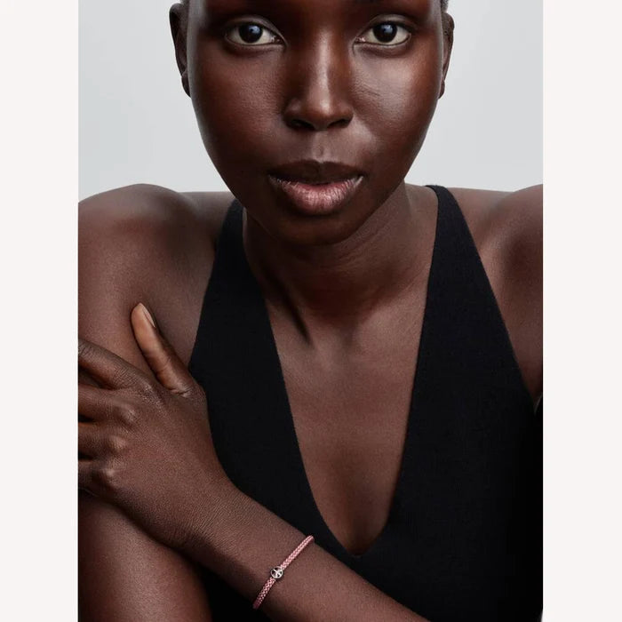 Woman wearing a pink bracelet with a silver peace symbol charm