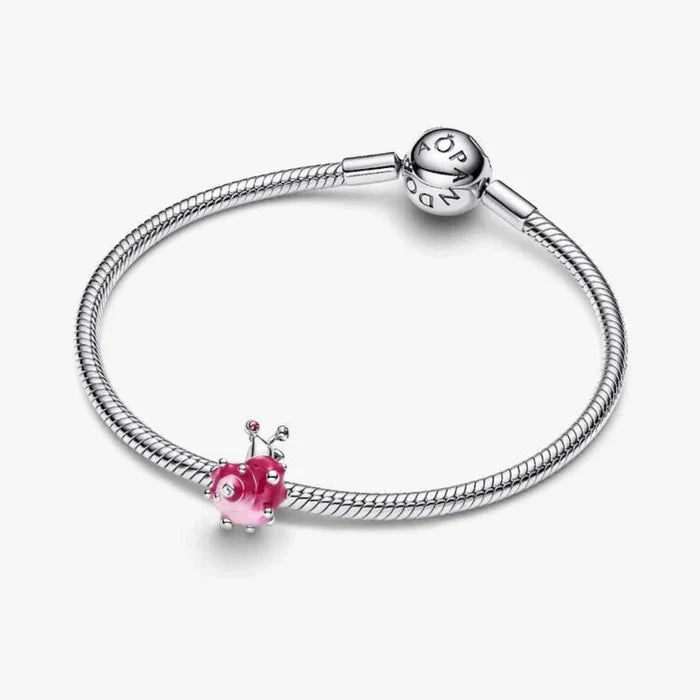 Silver bracelet with a pink heart charm on a white background