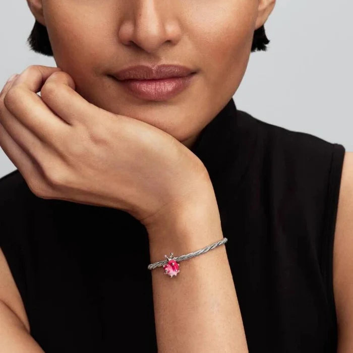 Woman wearing a bracelet with a pink gemstone on a gray background