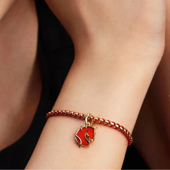 Bracelet with a red heart charm on a wrist