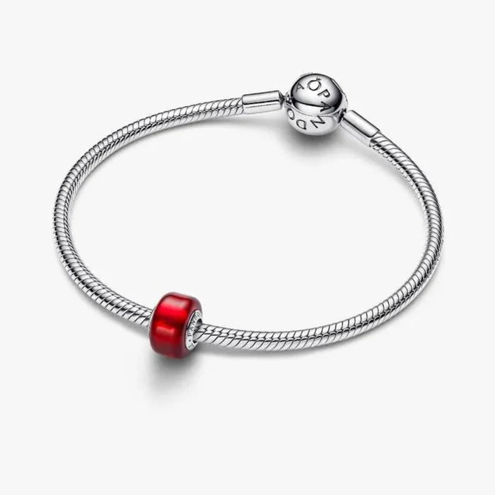 Silver bracelet with a red charm on a white background