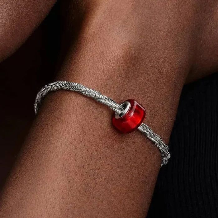 Bracelet with a red bead on a wrist against a dark background