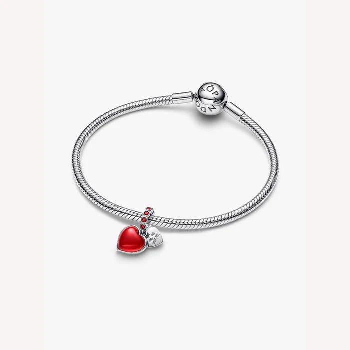 Silver bracelet with a red heart charm on a light background