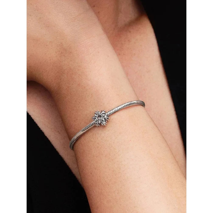 Model wearing Pandora Snowflake Charm on a silver bracelet, close-up wrist shot showing charm details.