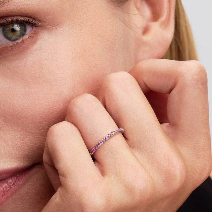 Close-up of a woman’s hand wearing the Pandora Sparkling Pink Band Ring in sterling silver with pink stones.