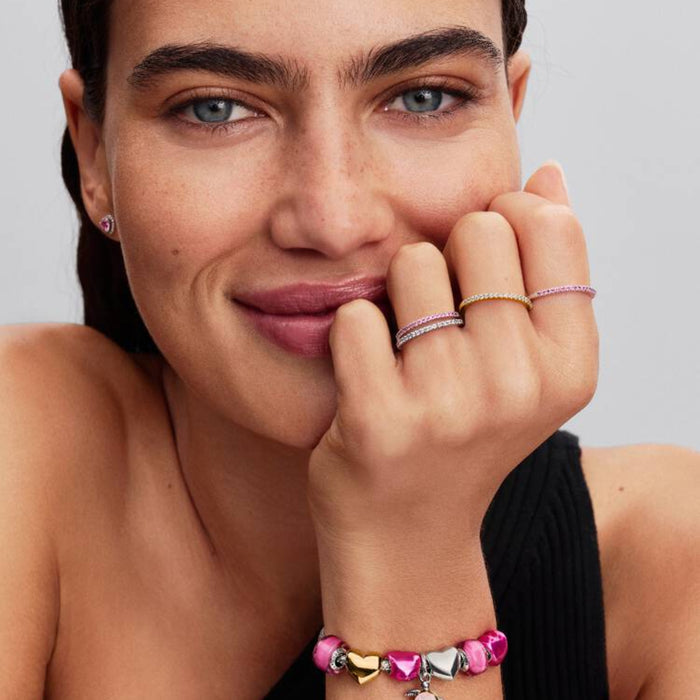 Pandora Sparkling Pink Band Ring in sterling silver worn on a woman’s finger, paired with other rings and a bracelet.