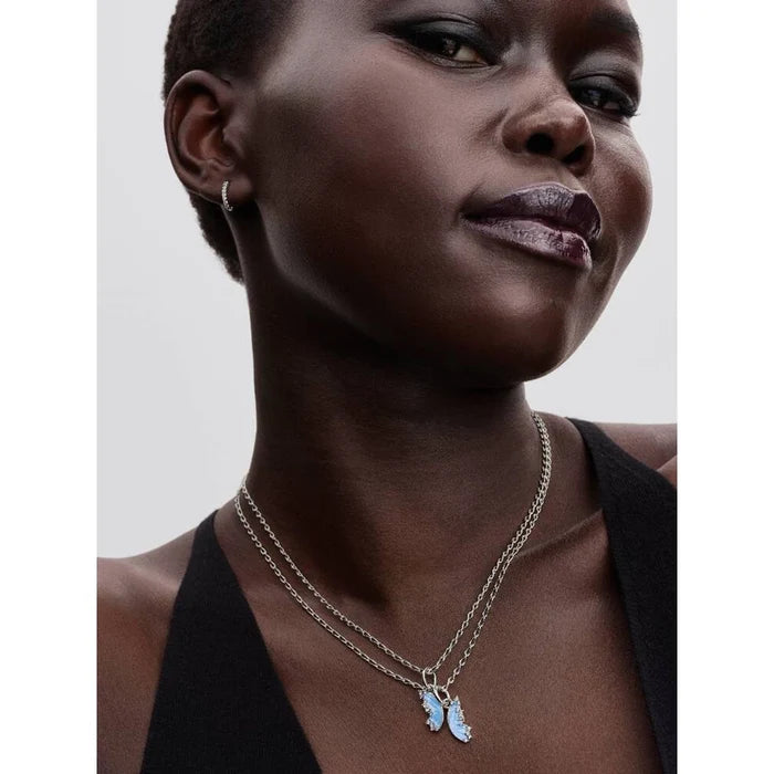 Woman wearing the Pandora Splittable Butterfly Dangle Charm as a pendant on layered silver necklaces.