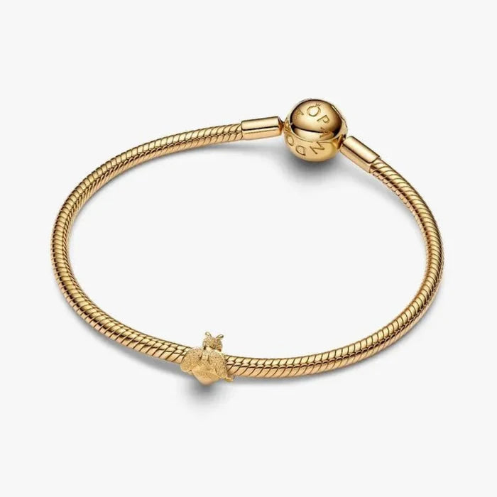 Gold bracelet with a bee charm on a white background