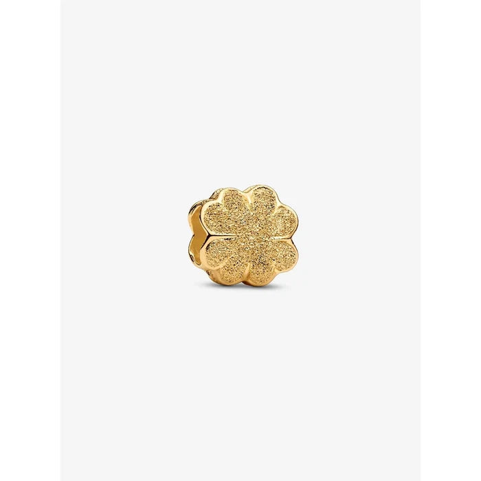 A close-up of a textured gold-plated four-leaf clover charm with sparkling detail.