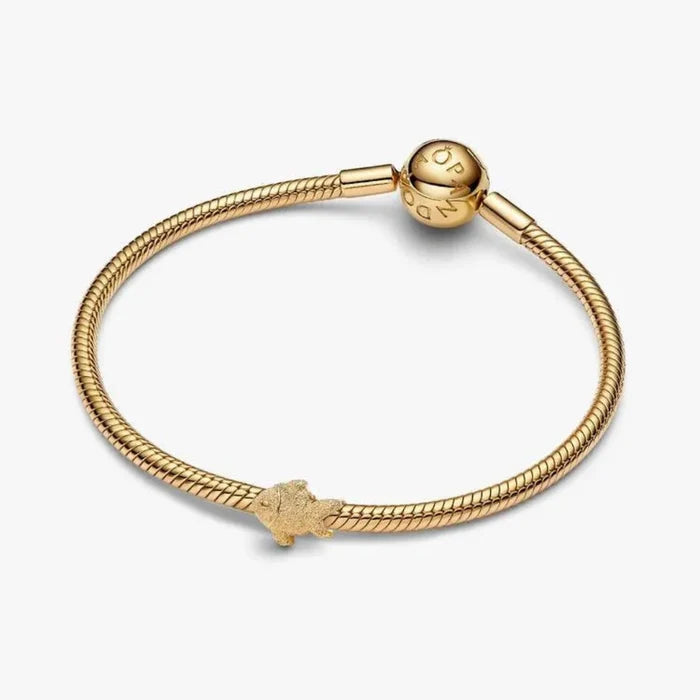 Gold bracelet with a small charm on a white background