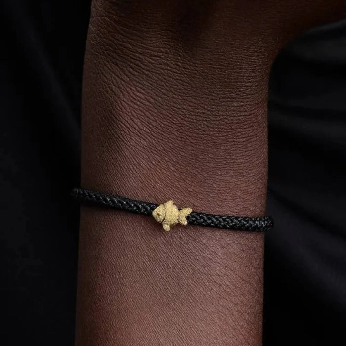 Bracelet with a gold clasp on a wrist against a dark background