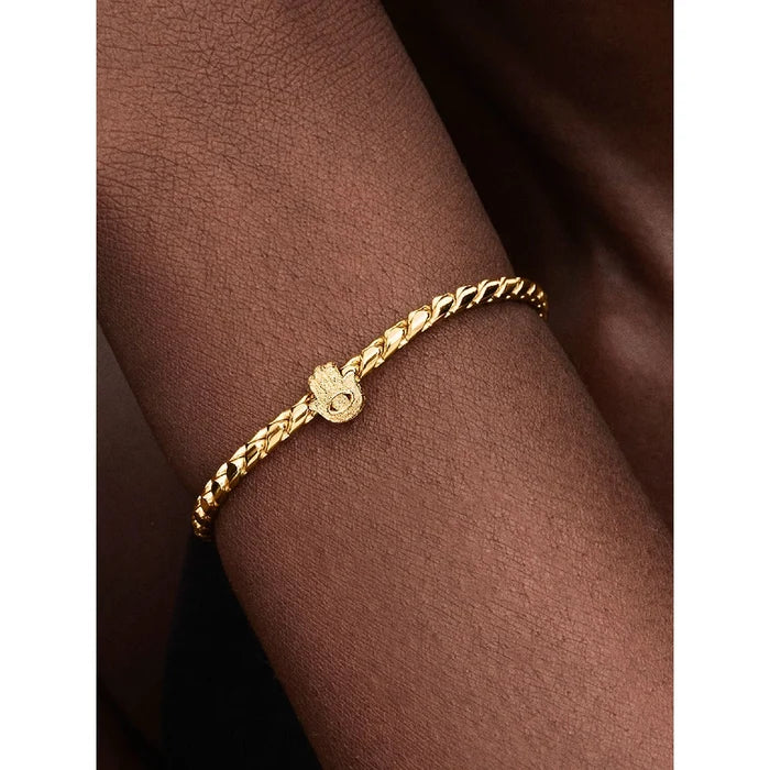 Woman wearing a gold bracelet featuring the Hamsa Hand charm with protective eye design.