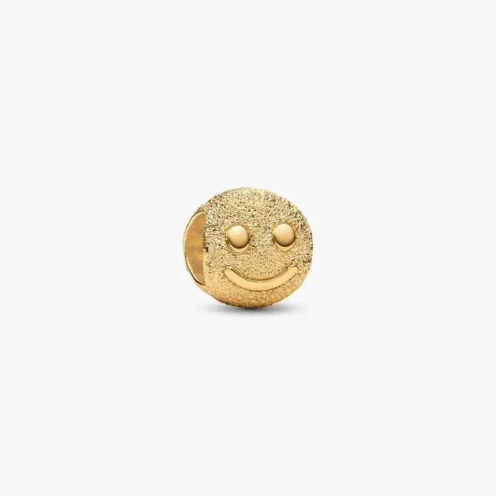 Gold smiley face charm on a white background