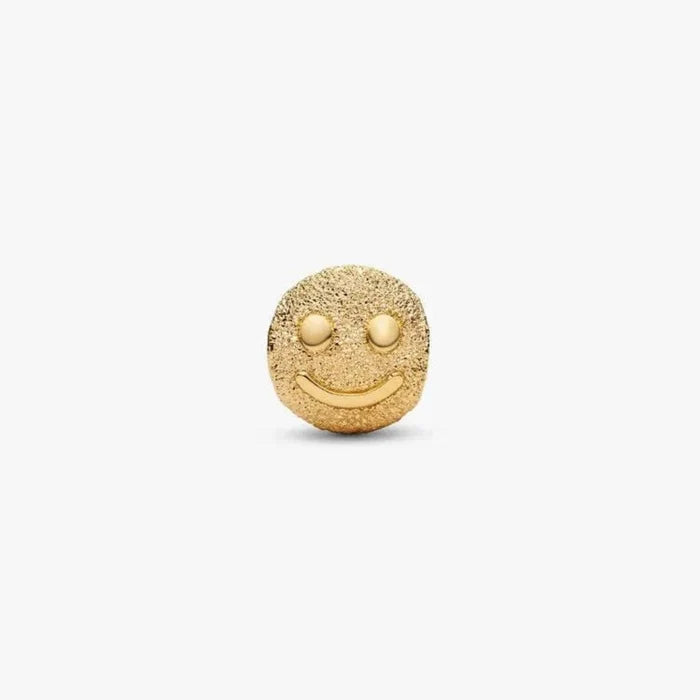 Gold smiley face charm on a white background