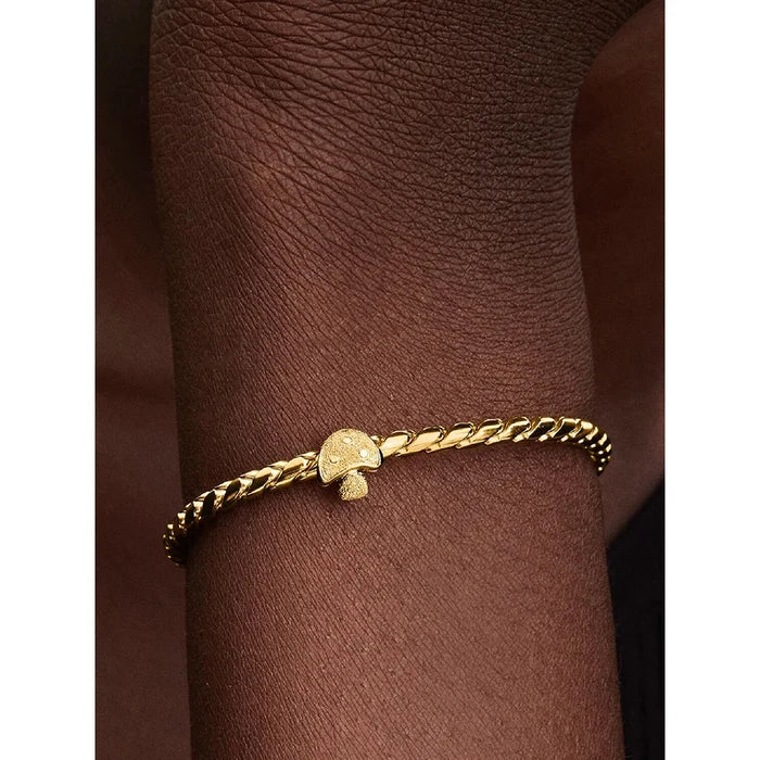 Gold mushroom charm on chain bracelet styled on model’s wrist