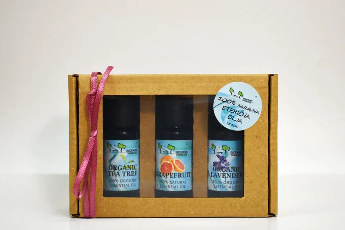 Three essential oil bottles in a cardboard box with a pink ribbon on a white background