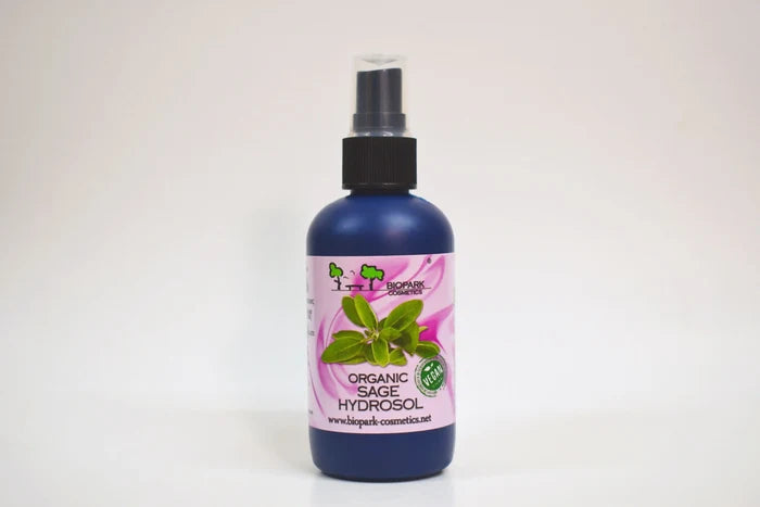Bottle of organic sage hydrosol with a pink label on a white background