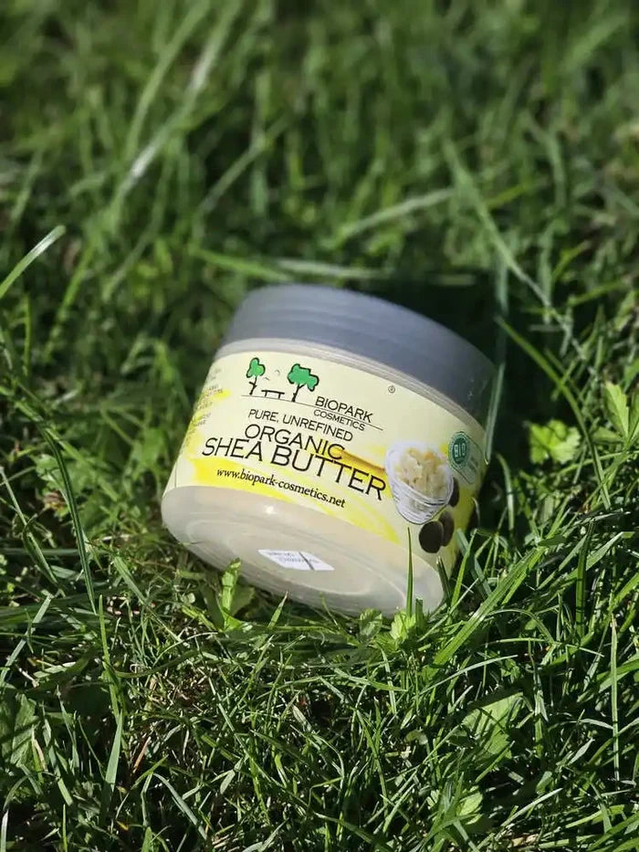 A jar of BioPark Organics Organic Shea Butter resting on a bed of green grass.