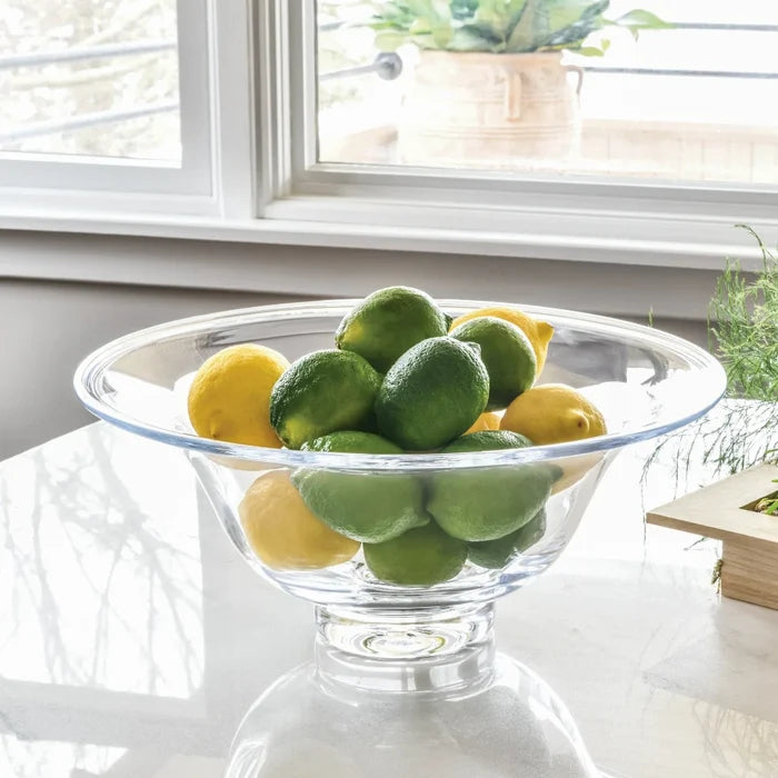 A bowl filled with fresh fruit, such as grapes, apples, and bananas, sitting on a rustic wooden table.