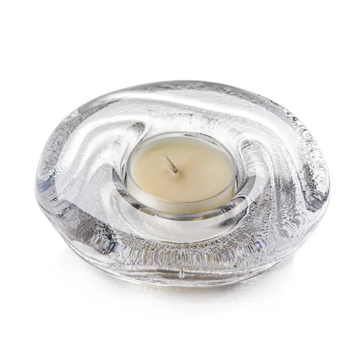 Clear glass  teac candle holder with a lit tealight candle on a white background