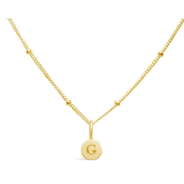 Stia Couture Mini G Love Letter Gold Necklace featuring an engraved G initial pendant in 14K gold plated sterling silver on a delicate Saturn chain.