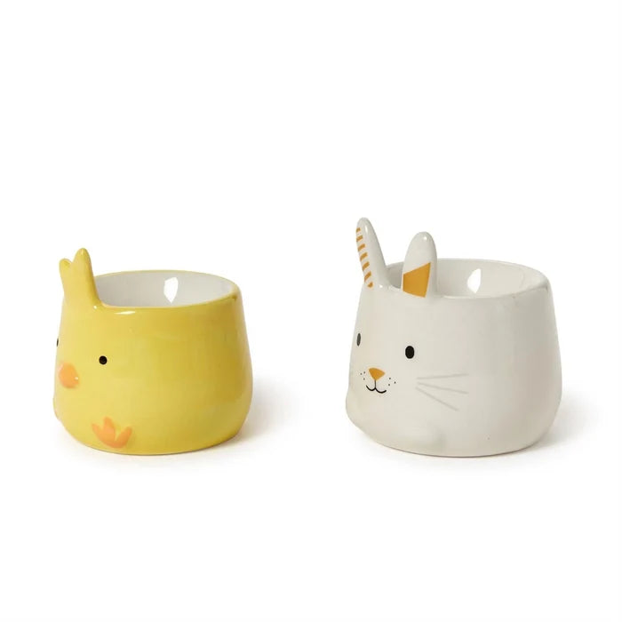Two ceramic cups featuring cute bunny and rabbit faces, perfect for a whimsical tea or coffee experience.