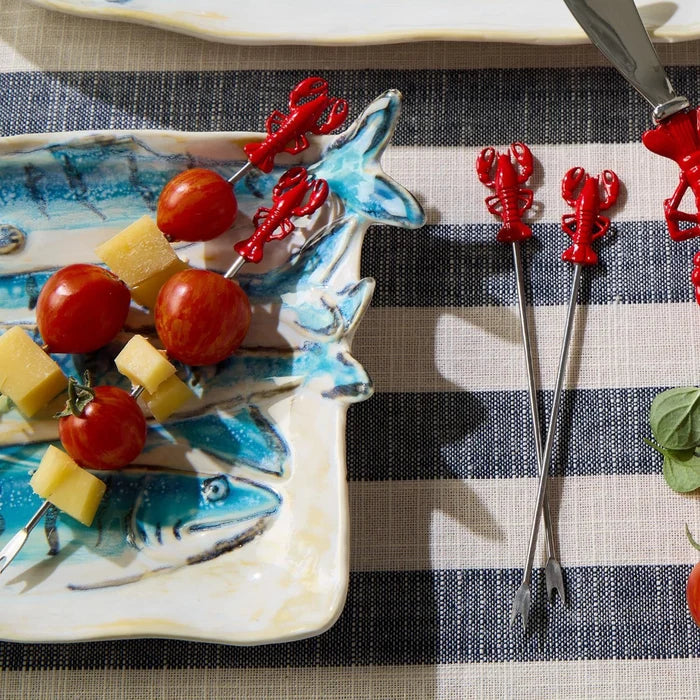 A dish displaying lobster skewers paired with ripe tomatoes on a white plate.