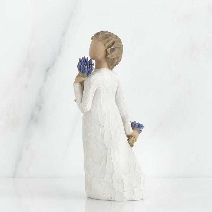 Statue of a person holding blue flowers against a white background
