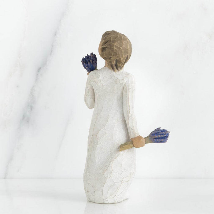 Statue of a woman holding blue flowers against a white background