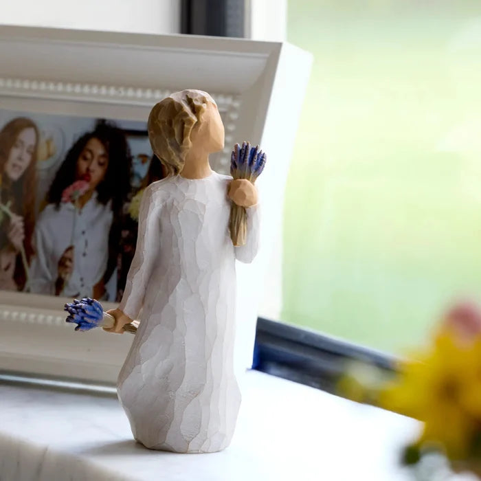 Decorative figurine of a woman holding flowers next to a framed photo on a surface.