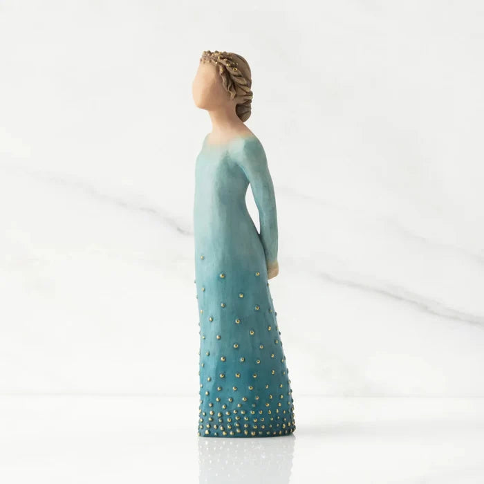 Statue of a woman in a long, light blue dress with gold accents on a white background