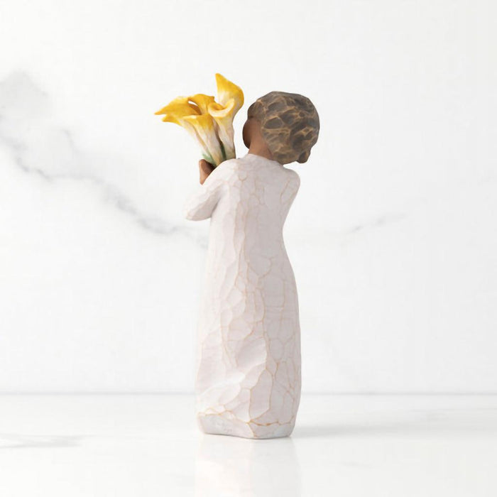 "Willow Tree With Gratitude figurine – hand-painted resin sculpture of a woman with darker skin tone holding a bouquet of yellow calla lilies in appreciation"