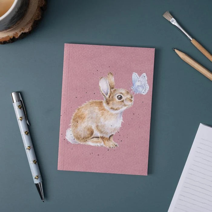 Wrendale Designs 'I Spy a Butterfly' rabbit notebook on a desk with a pen, pencils, and coffee cup – perfect stationery gift.