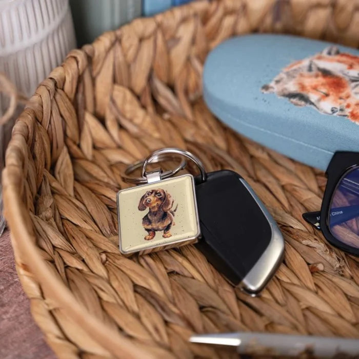 A square key chain displays a dachshund dog, highlighting its unique shape and charming personality.