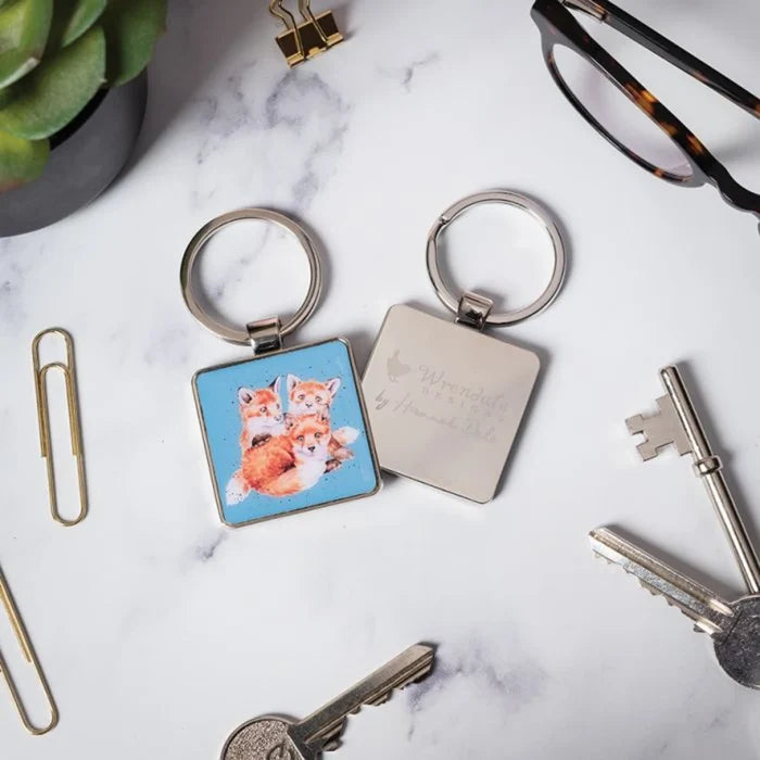 A keychain displaying two stylized foxes, one with a bushy tail and the other with a sleek design, both in vibrant colors.
