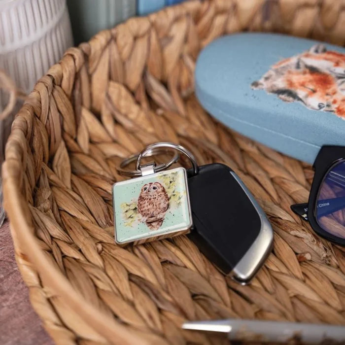 A square keychain featuring a detailed illustration of an owl against a solid background.