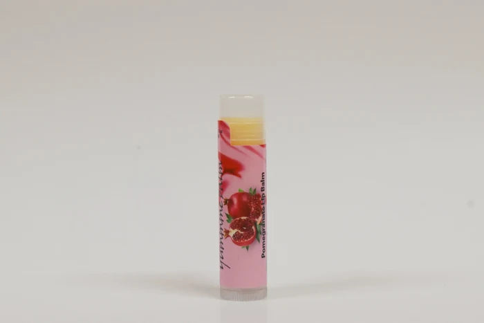Lip balm with a pink label featuring pomegranate graphics on a white background